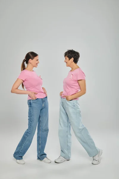Conceito de câncer de mama, campanha de apoio, duas mulheres olhando uma para a outra, sorriso, fundo cinza — Fotografia de Stock