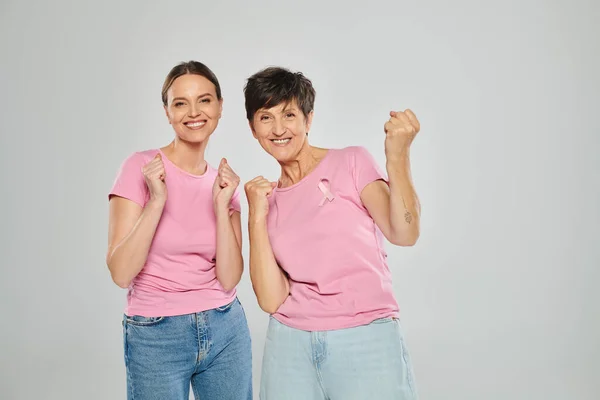 Концепция рака молочной железы, возбужденные женщины смотрят в камеру и жестикулируют на сером фоне, да, да — стоковое фото