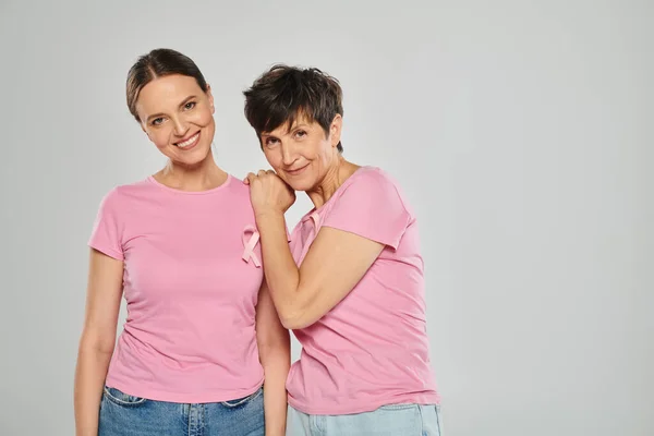 Breast cancer awareness concept, happy women with pink ribbons on grey backdrop, cancer free — Stock Photo