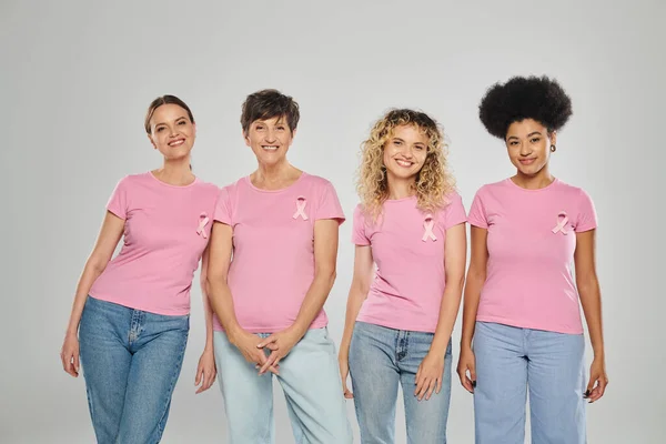 Breast cancer awareness concept, interracial women with pink ribbons on grey backdrop, diversity — Stock Photo