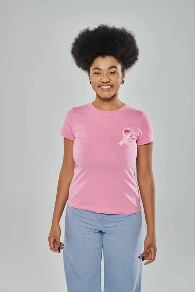 Consciência do câncer de mama, mulher americana africana com fita rosa no fundo cinza, diversidade, sorriso — Fotografia de Stock