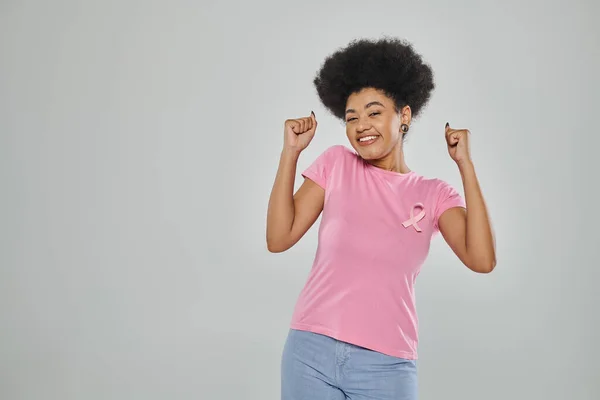Consapevolezza del cancro al seno, donna afroamericana eccitata con nastro rosa su grigio, senza cancro — Foto stock