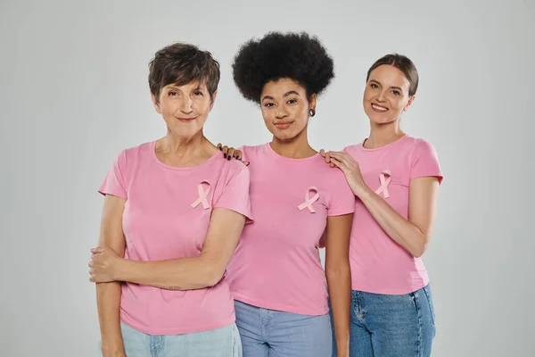 Consapevolezza del cancro al seno, felici donne multiculturali sorridenti su sfondo grigio, generazioni diverse — Foto stock