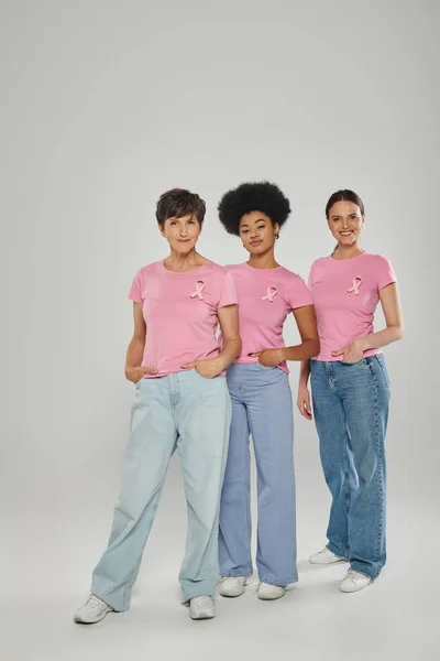 Breast cancer awareness, multicultural women smiling, posing on grey backdrop, different generations — Stock Photo