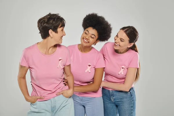 Sensibilisation au cancer du sein, femmes interracial souriantes, posant sur fond gris, différentes générations — Photo de stock