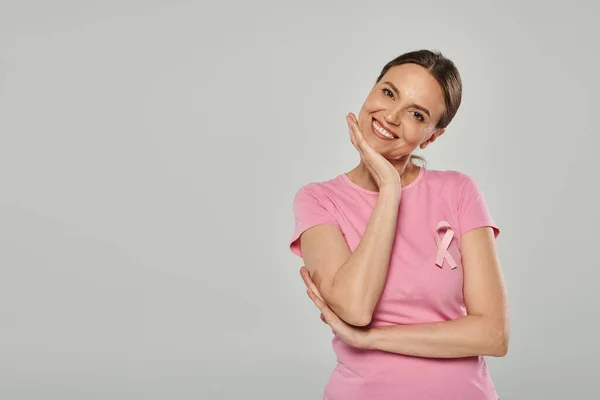 Felice donna con nastro rosa su sfondo grigio, consapevolezza del cancro al seno, cancro libero, sorriso e gioia — Foto stock
