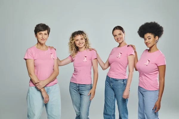 Multiracial women different age standing on grey backdrop, support, breast cancer awareness — Stock Photo