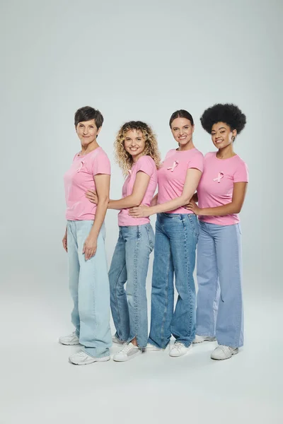 Interrazziale donne di età diversa sorridente su sfondo grigio, gioia, consapevolezza del cancro al seno, sostegno — Foto stock