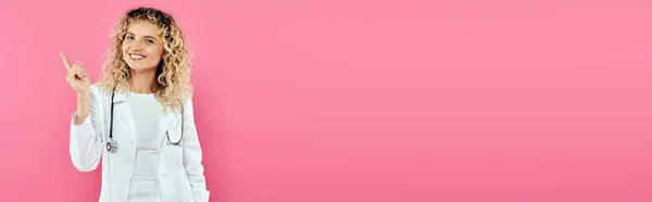 Concept de sensibilisation au cancer du sein, femme heureuse médecin pointant vers le haut, fond rose, joie, femme, bannière — Photo de stock