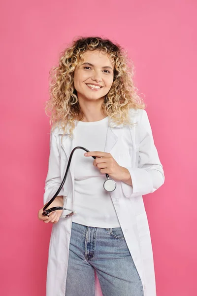 Breast cancer awareness concept, happy female doctor holding stethoscope, pink backdrop, woman — Stock Photo