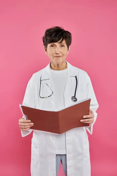 Oncologista maduro, médico mulher segurando pasta, conceito de consciência do câncer de mama, diagnóstico — Fotografia de Stock
