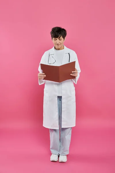 Онколог-женщина, зрелый врач с папкой в руках, концепция информированности о раке молочной железы, медицинская карта — стоковое фото