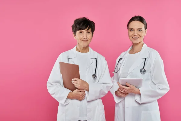Женщины-онкологи, врачи цифрового возраста, таблетки, папки, медицинские записи, осведомленность о раке молочной железы — стоковое фото