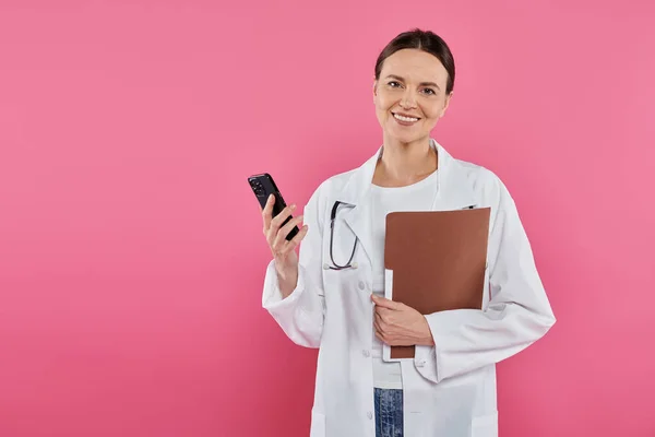 Consciência do câncer de mama, médico feminino, oncologista feliz com pasta usando smartphone, era digital — Fotografia de Stock