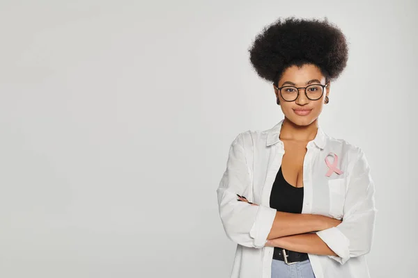 Afrikanisch-amerikanische Frau mit rosa Schleife des Brustkrebsbewusstseins kreuzt Arme isoliert auf grau — Stockfoto