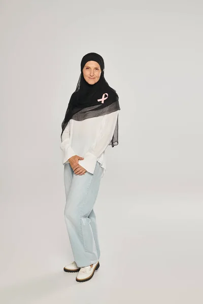 Lächelnde Frau im Hijab mit rosa Schleife des Brustkrebsbewusstseins auf grauem Hintergrund — Stockfoto