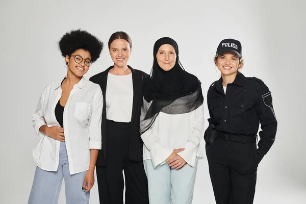 Alegre grupo de mujeres multiétnicas posando juntas aisladas en gris - foto de stock