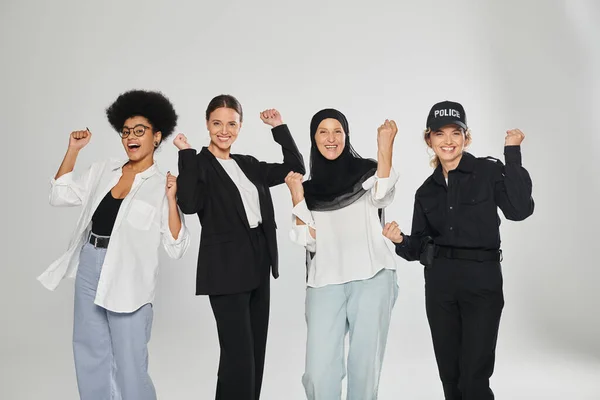 Grupo excitado de diferentes mujeres multiétnicas mostrando sí gesto aislado en gris - foto de stock