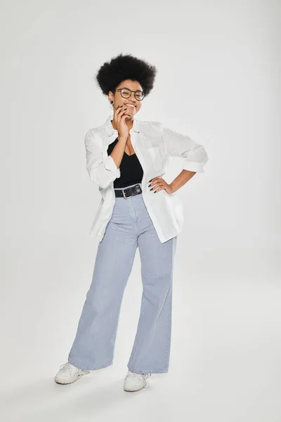 Full length of stylish and smiling african american woman posing on grey background — Stock Photo