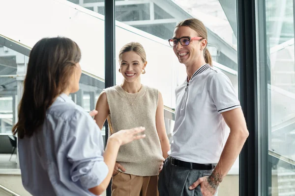 Jovens colegas de trabalho alegres em negócios roupas casuais conversando e sorrindo uns para os outros, co-trabalhando — Fotografia de Stock