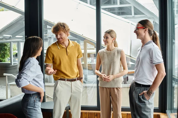 Quatro colegas de trabalho em roupas casuais de negócios alegremente conversando uns com os outros, conceito de coworking — Fotografia de Stock