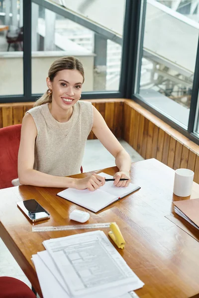 Young female employee working with documents at table looking at camera, coworking concept — Stock Photo