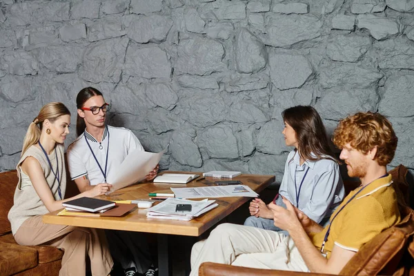 Four young colleagues in business casual attire doing their paperwork at table, coworking concept — Stock Photo