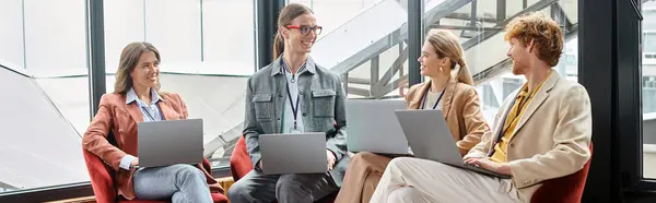 Quatre collègues souriants souriants et travaillant sur des ordinateurs portables avec toile de fond en verre, coworking, bannière — Photo de stock