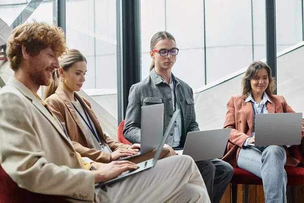 Focused young team in smart attire working on their laptops with window on background, coworking — Stock Photo