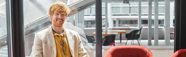 Smiling red haired employee in smart outfit looking at camera with glass backdrop, coworking, banner — Stock Photo