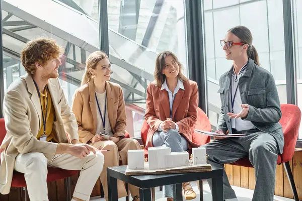 Bright creative team discussing their scale model of building with window on backdrop, design bureau — Stock Photo
