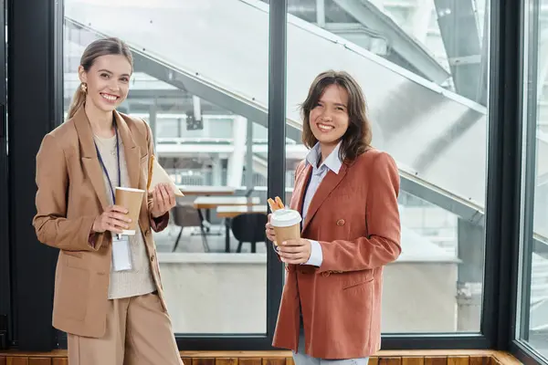 Елегантні колеги в ділових повсякденних вбраннях посміхаються і насолоджуються кавою і бутербродами, коворкінгом — стокове фото