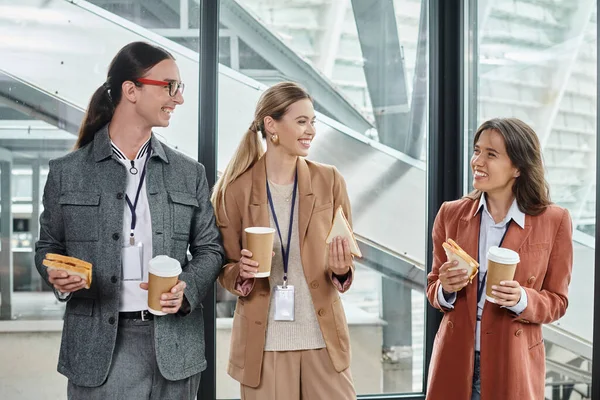 Three colleagues having lunch break smiling sincerely and eating sandwiches, coworking concept — Stock Photo