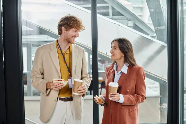 Compañeros alegres en traje casual inteligente charlando y comiendo su almuerzo con café, coworking - foto de stock