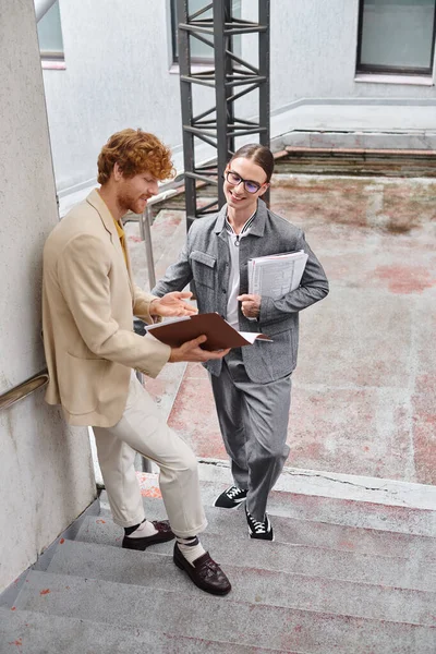 Dos joven teniendo descanso al aire libre sonriendo y discutiendo su papeleo, concepto de coworking - foto de stock