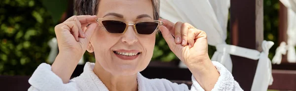 Happy middle aged woman wearing sunglasses and looking at camera during wellness retreat, banner — Stock Photo