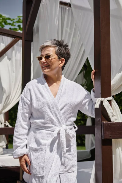 Glückliche reife Frau mit Sonnenbrille, die sich im privaten Pavillon ausruht, Wellness-Rückzugsort im Luxus-Resort — Stockfoto