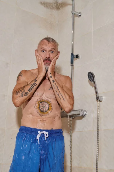 Drôle d'homme d'âge moyen avec tatouages prenant douche et lavage visage, hygiène personnelle — Photo de stock
