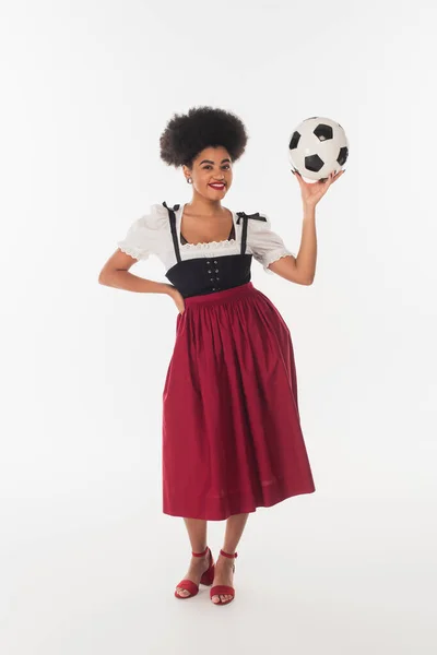 Seducente cameriera bavarese africana americana in abito autentico in posa con pallone da calcio su bianco — Foto stock