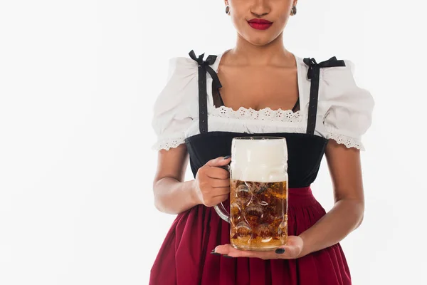 Cropped african american bavarian waitress in dirndl with mug of beer on white, oktoberfest — Stock Photo