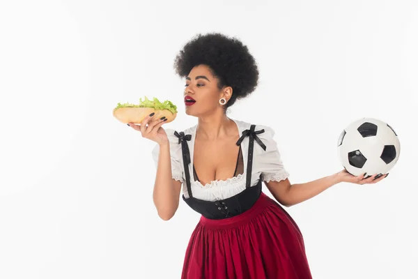 African american bavarian waitress with mug of beer opening mouth near tasty hot dog on white — Stock Photo