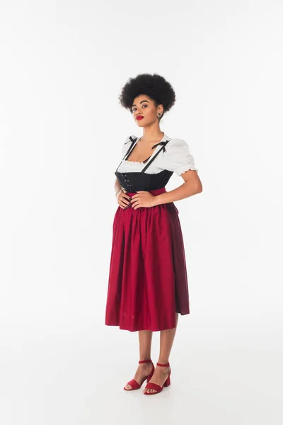 Confident african american oktoberfest waitress in traditional bavarian costume standing on white — Stock Photo