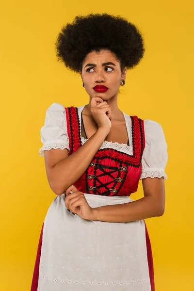 Upset african american oktoberfest waitress in traditional costume looking away on yellow — Stock Photo