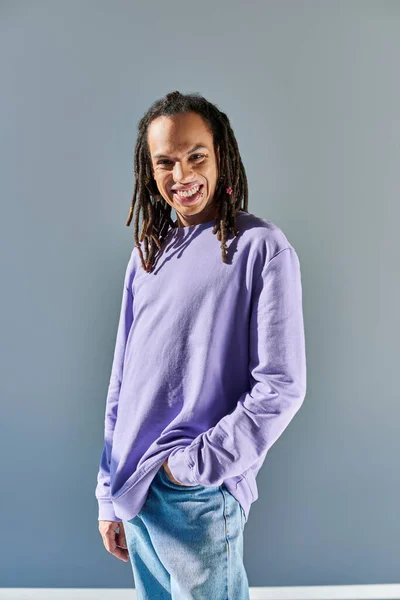Fröhlicher junger afrikanisch-amerikanischer Mann in lässigem lila Sweatshirt, der in die Kamera blickt und lächelt — Stockfoto