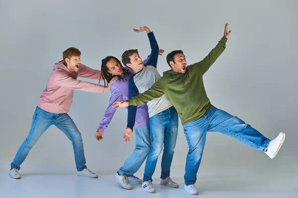 Vier fröhliche Freunde in hellen, lässigen Outfits, die Spaß auf grauem Hintergrund haben, kulturelle Vielfalt — Stockfoto