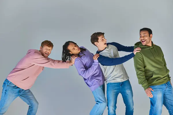 Четыре улыбающиеся счастливые мужчины в повседневной городской одежде отлично проводят время на сером фоне, культурное разнообразие — стоковое фото