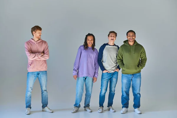 Jovens amigos em roupas cotidianas sorrindo sinceramente e posando em pano de fundo cinza, diversidade cultural — Fotografia de Stock