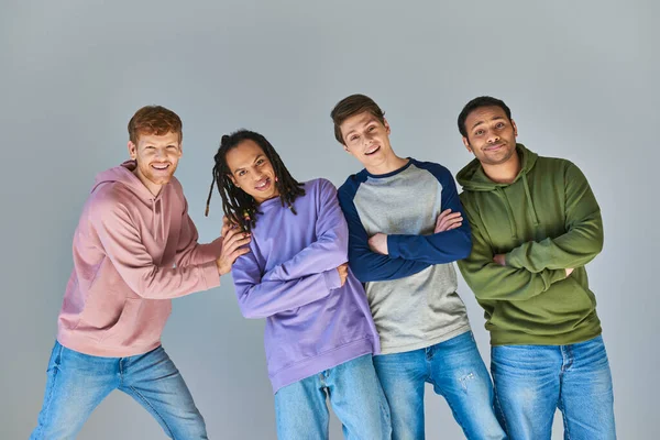 Quatre hommes joyeux en tenue décontractée souriant à la caméra posant sur fond gris, diversité culturelle — Photo de stock