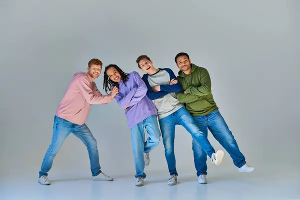 Cheerful friends in casual outfits having great time posing on grey backdrop, cultural diversity — Stock Photo