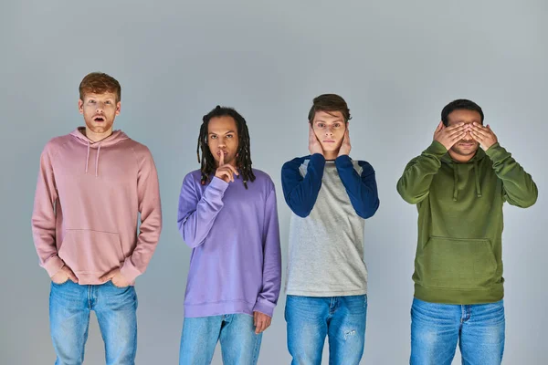 Vier Freunde in lässiger heller Kleidung stehen und gestikulieren auf grauem Hintergrund, kulturelle Vielfalt — Stockfoto